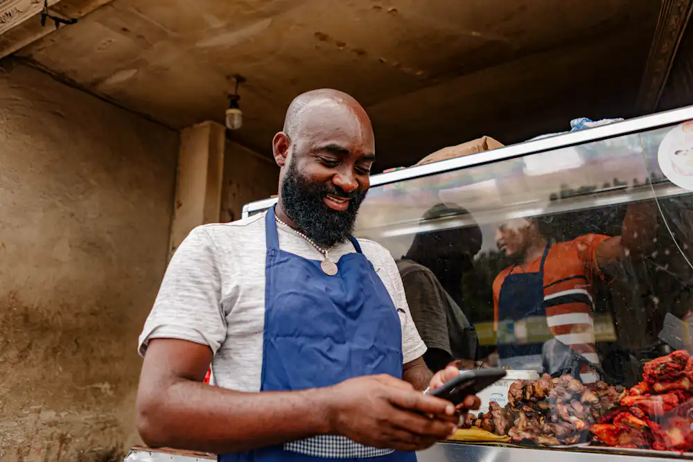 African small business owner using a smartphone to manage local business visibility