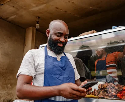 African small business owner using a smartphone to manage local business visibility